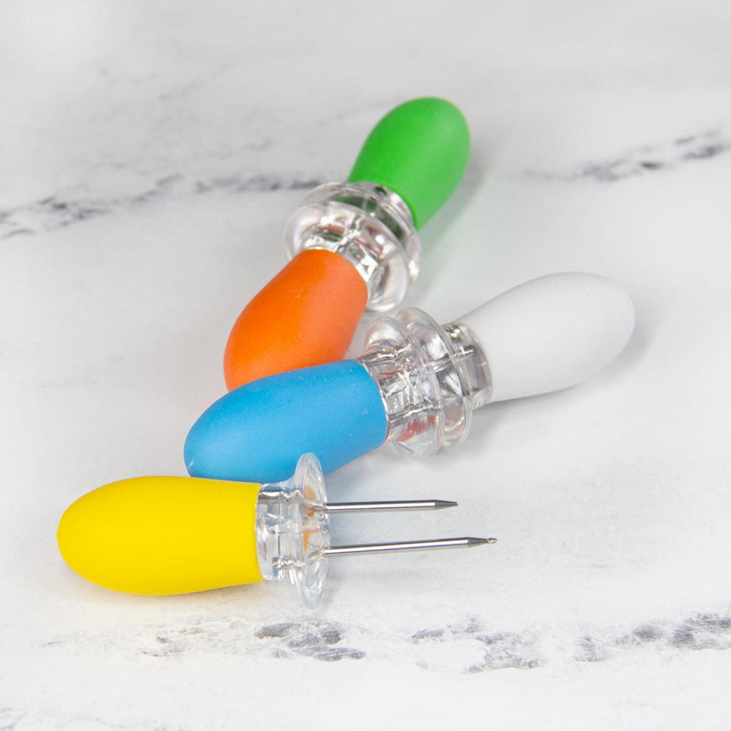 A set of Corn on the Cob Holders with Stainless Steel Prongs & Silicone Grips by XSpecial Marketplace on a marble surface.