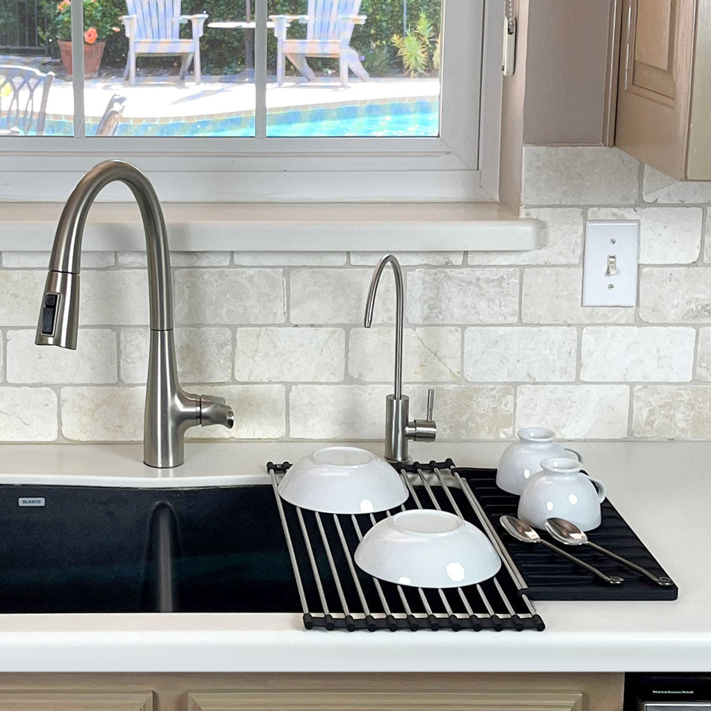 A kitchen with an Over Sink Roll-Up Dish Drying Rack from Grand Fusion Housewares, LLC and a window.