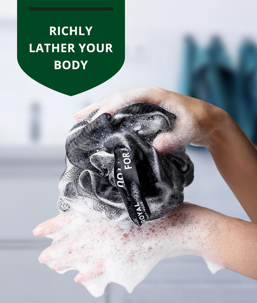 A woman is washing her body with a Loofah Bath Sponge Set Of 3 by Royal Craft Wood towel, perfect for foodies who appreciate high-quality kitchen tools like the Blade Meat Tenderizer Tool
