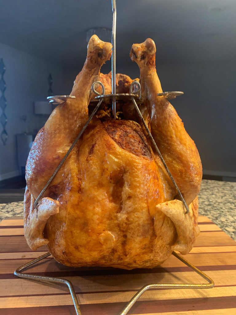A Turbo Trusser for Chicken or Turkey, featured on Shark Tank, a must-have blade meat tenderizer tool for foodies and meat lovers, sitting on top of a wooden cutting board by Grand
