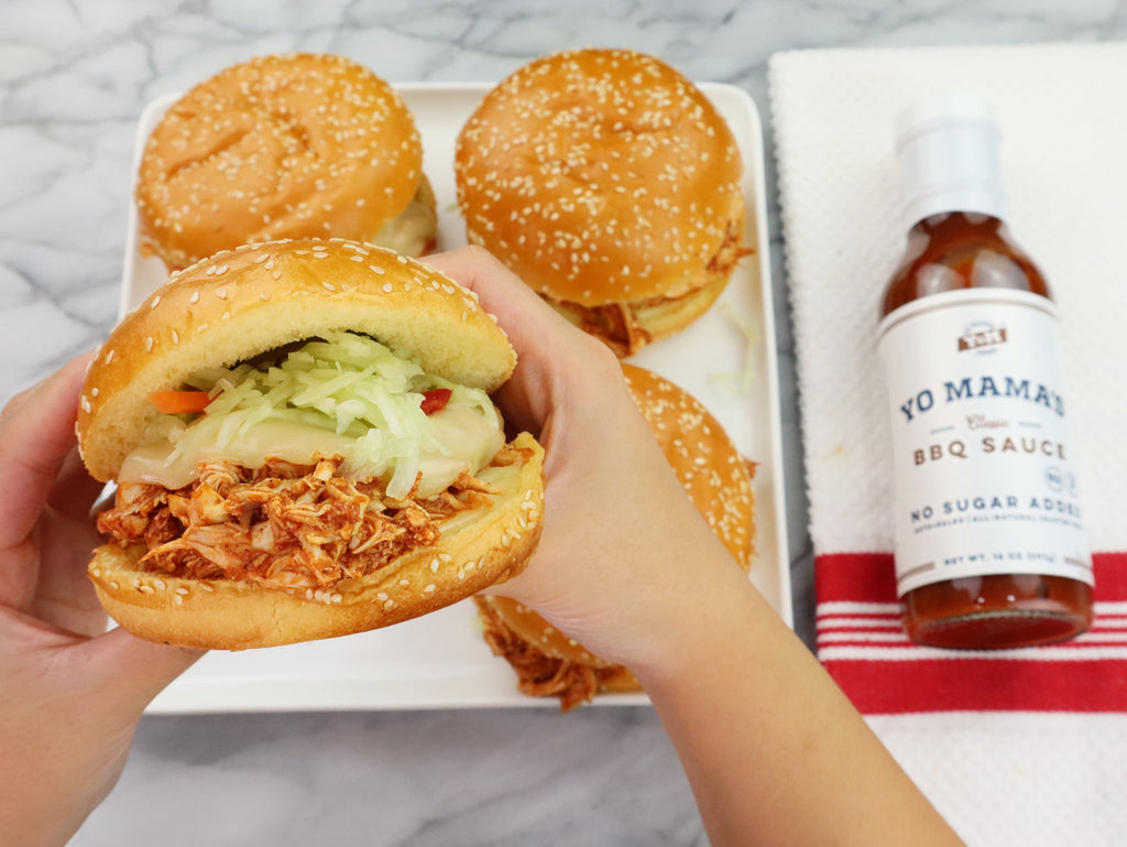 A person is holding two Classic BBQ sliders next to a bottle of Yo Mama's Foods BBQ sauce in XSpecial Marketplace.