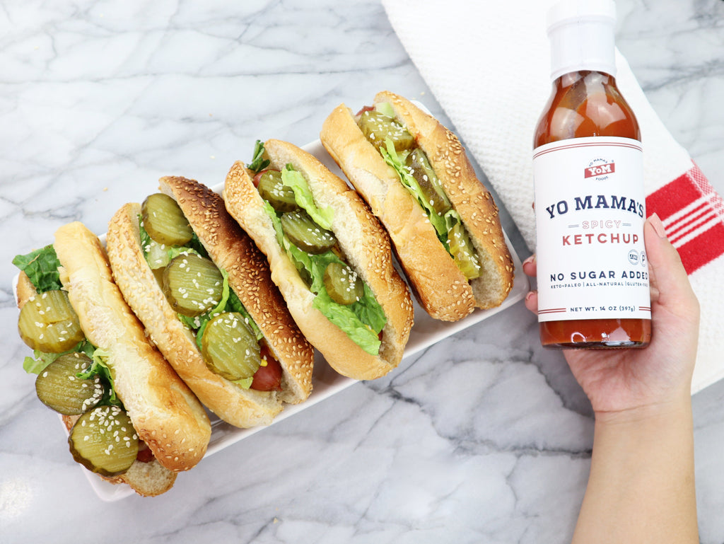 A person holding a tray of XSpecial sandwiches and a bottle of Spicy Ketchup (Keto and Paleo Certified) by Yo Mama's Foods.