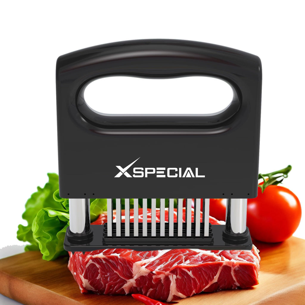 The XSpecial Mini-Deluxe Meat Tenderizer Tool, featuring a black handle and stainless steel blades, rests on raw meat on a wooden board. It's surrounded by lettuce, tomatoes, and a chili pepper, demonstrating an essential tool for culinary enthusiasts.