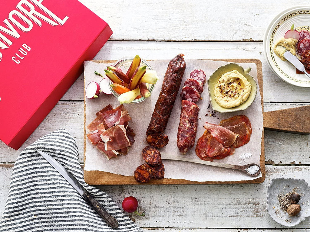A Carnivore Club Classic Box Sampler by Carnivore Club USA with a variety of meats on it, perfect for foodies.