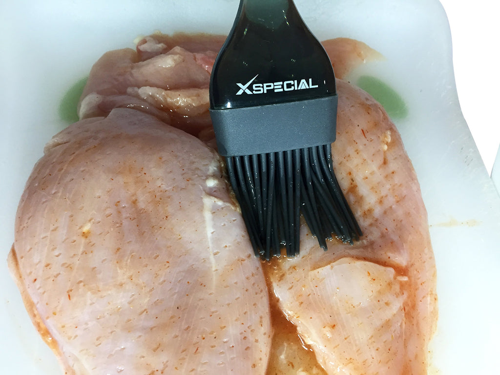 A Cooking Brush By XSpecial is being used to clean chicken in a dish in the kitchen.