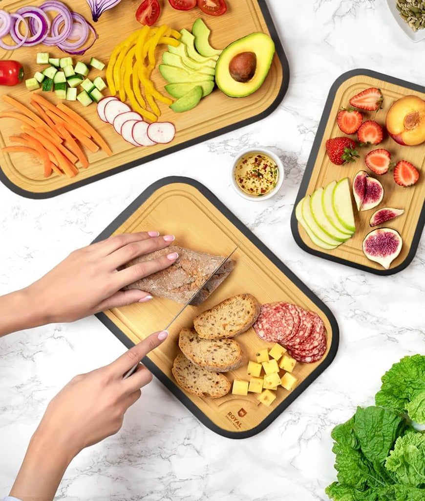 A foodie using a blade meat tenderizer tool on a Royal Craft Wood black wood cutting board set of 3 for cutting vegetables.