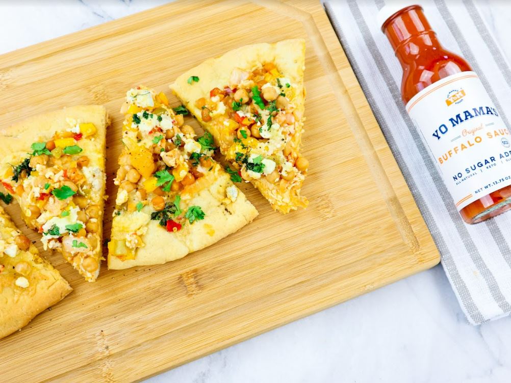 Four slices of Classic Buffalo pizza from Yo Mama's Foods on a cutting board, perfect for foodies.