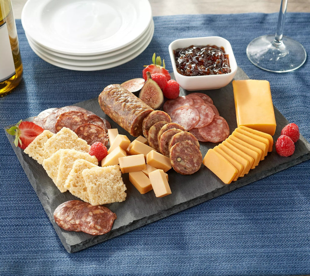 A Carnivore Club USA slate platter with meat, cheese, crackers, and fruit for foodies and meat lovers.