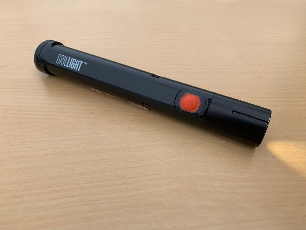 A XSpecial Meat Tenderizer Tool with a red light sitting on top of a wooden table.