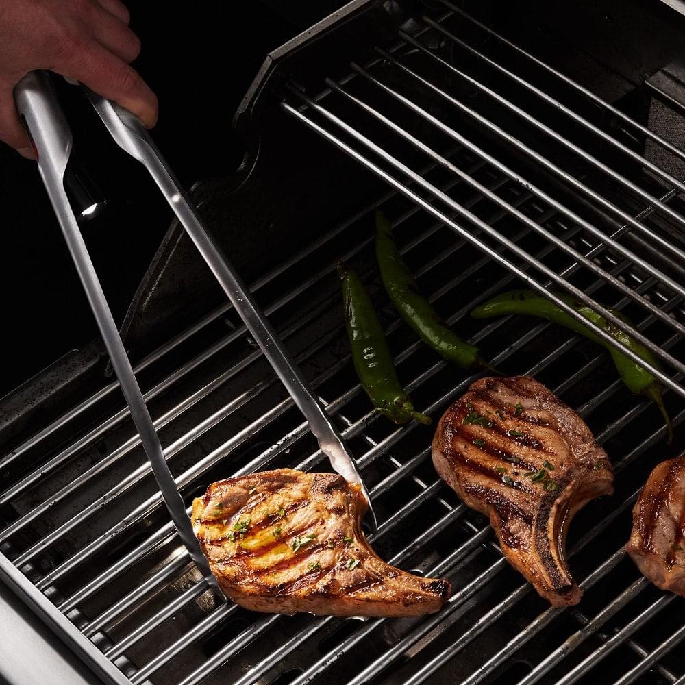 A person is grilling steaks on a Grill Light Gift 2 Set grill from Grillight.com using the XSpecial Meat Tenderizer Tool.