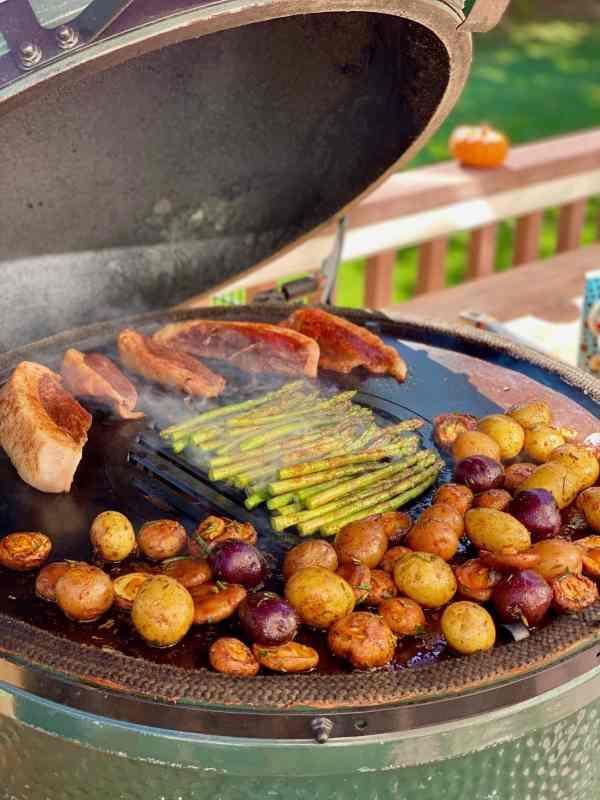 An XSpecial Green Egg Style / Kamado Style Plancha Griddle from XSpecial Marketplace with potatoes and meat on it, perfect for foodies.