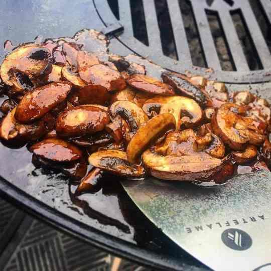 Mushrooms being cooked on an Arteflame Outdoor Grills Green Egg Style / Kamado Style Plancha Griddle With Grill Grate Combination Insert from XSpecial Marketplace.