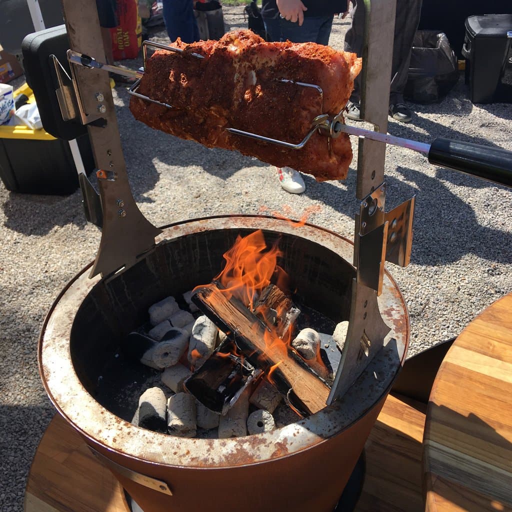 An XSpecial Meat Lovers' delight is being cooked on an Arteflame One Series 20" Grill in a fire pit.