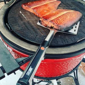 A salmon is being cooked on a grill using an XSpecial LED Spatula.