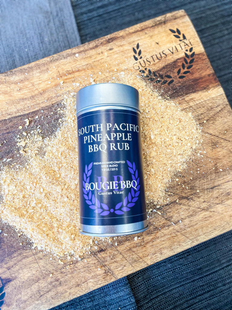 A tin of South Pacific Pineapple BBQ Rub & Seasoning by Gustus Vitae sitting on a cutting board.