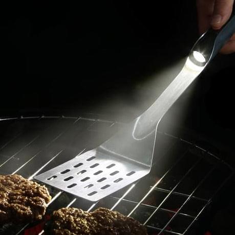 A person grilling burgers with a Grillight.com Grill Light Gift 2 Set spatula from the XSpecial Marketplace.